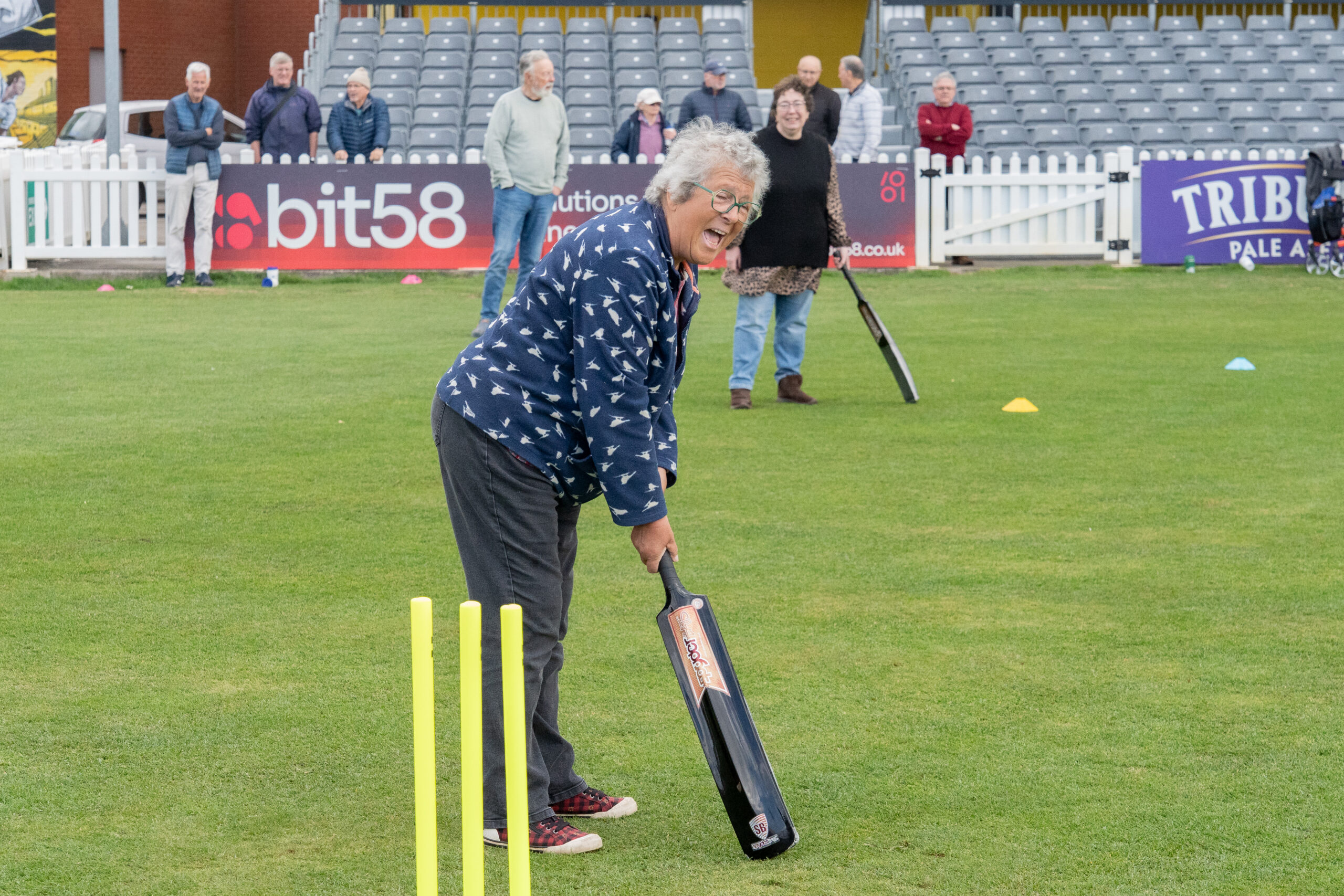 A woman smiles while waiting to bat during a walkers and talkers walking cricket taster session